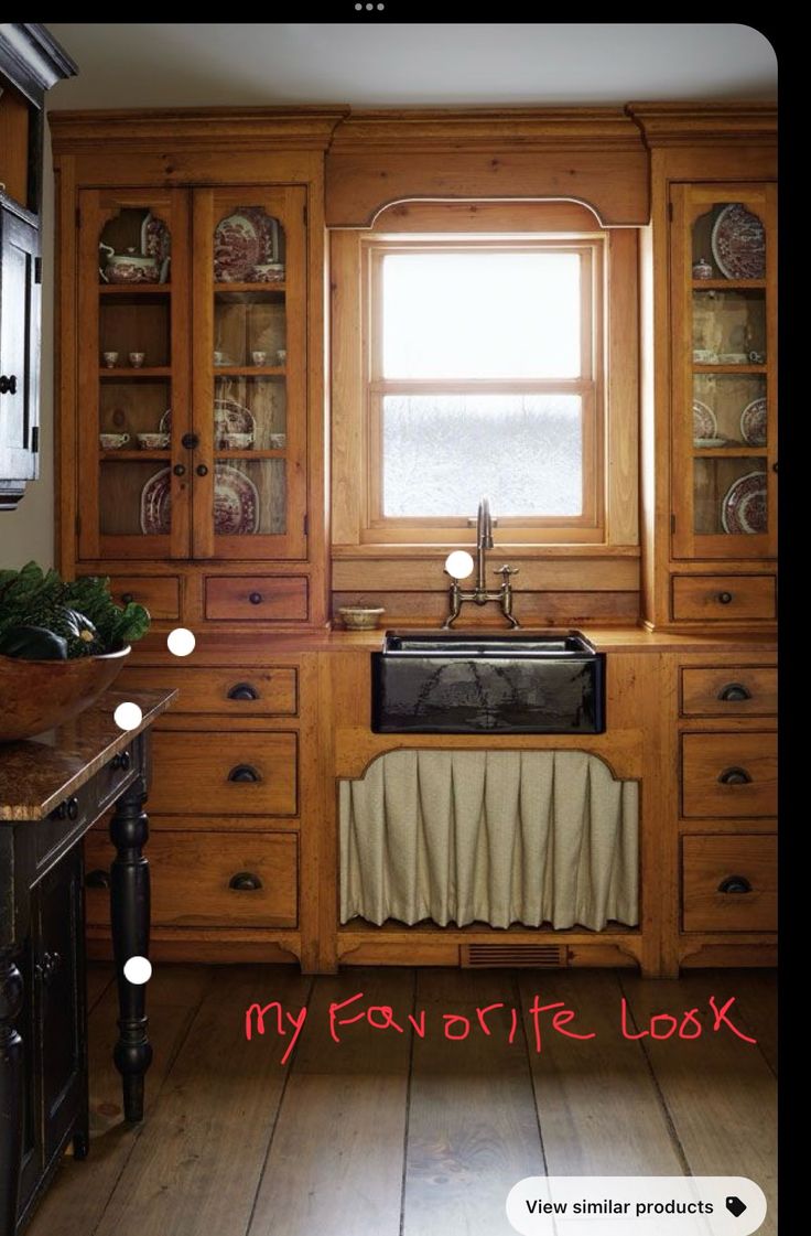 an old fashioned kitchen with wooden cabinets and a black sink in front of a window