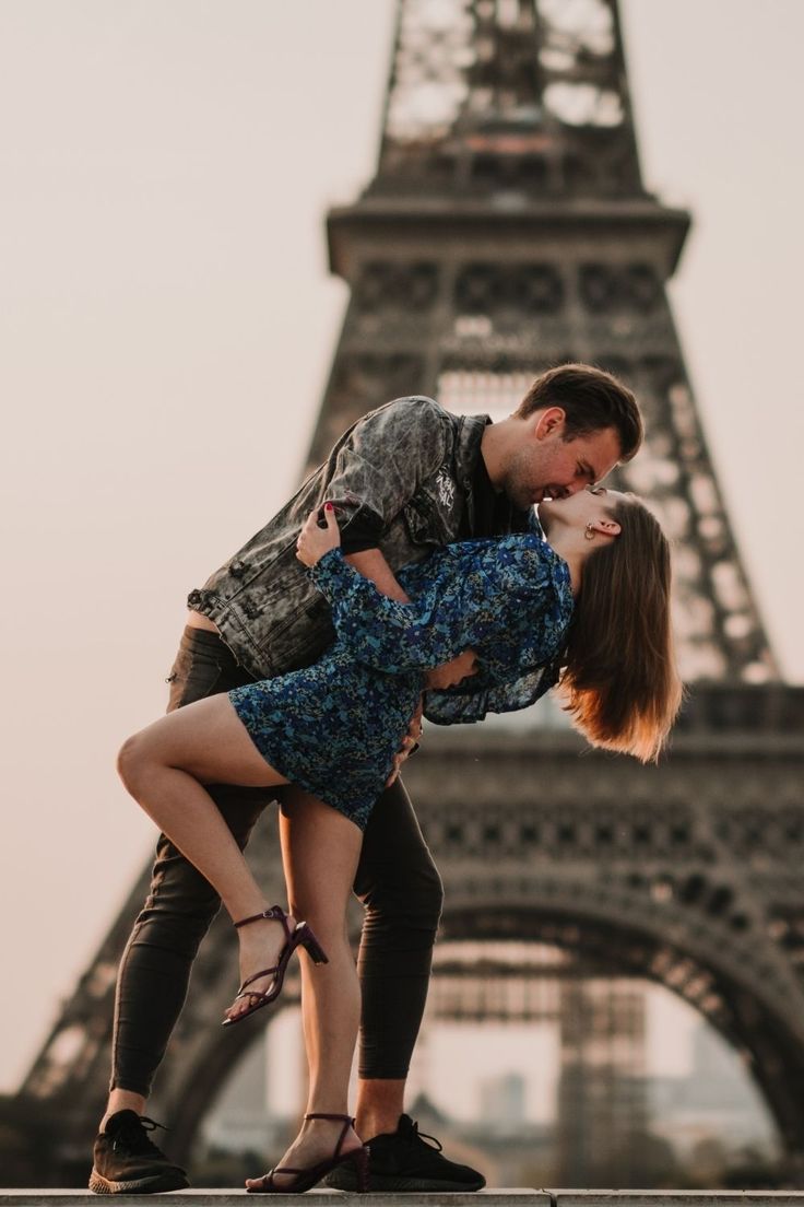 a man and woman are kissing in front of the eiffel tower, paris