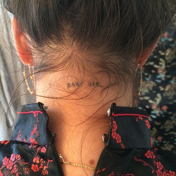 the back of a woman's neck with her name tattooed on it and flowers