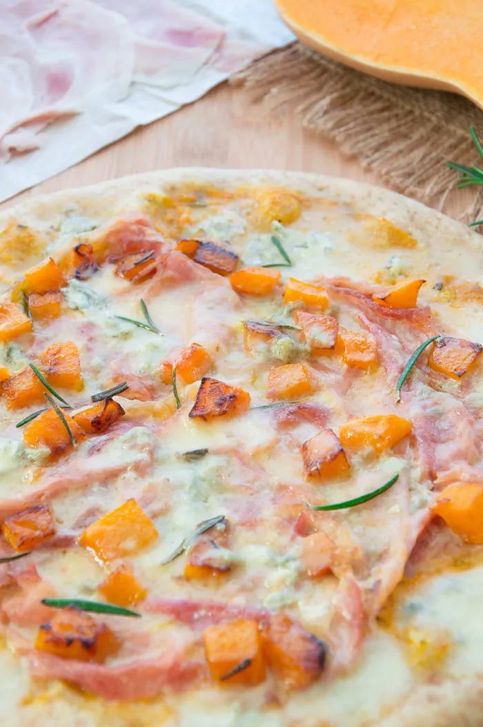 a pizza sitting on top of a wooden table covered in cheese and veggies