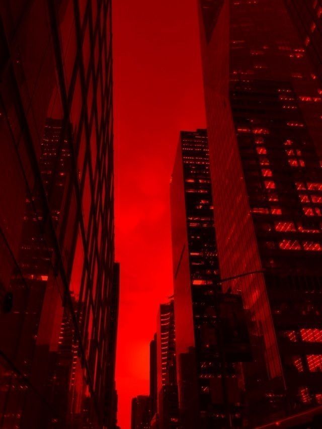 the sky is red and there are skyscrapers in the background