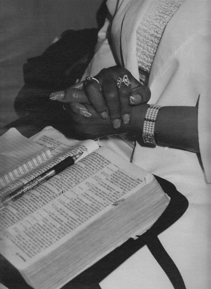 a black and white photo of a woman holding her hands over an open book with writing on it