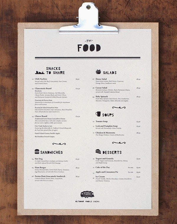 a clipboard with food menu on it hanging on a wooden wall next to a cup of coffee