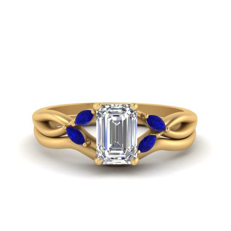 an emerald and blue sapphire engagement ring with leaves on the band, set in yellow gold