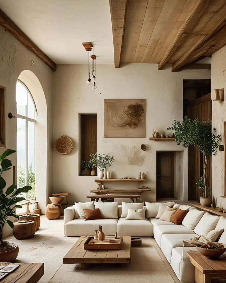 a living room filled with white couches and wooden tables next to an arched window