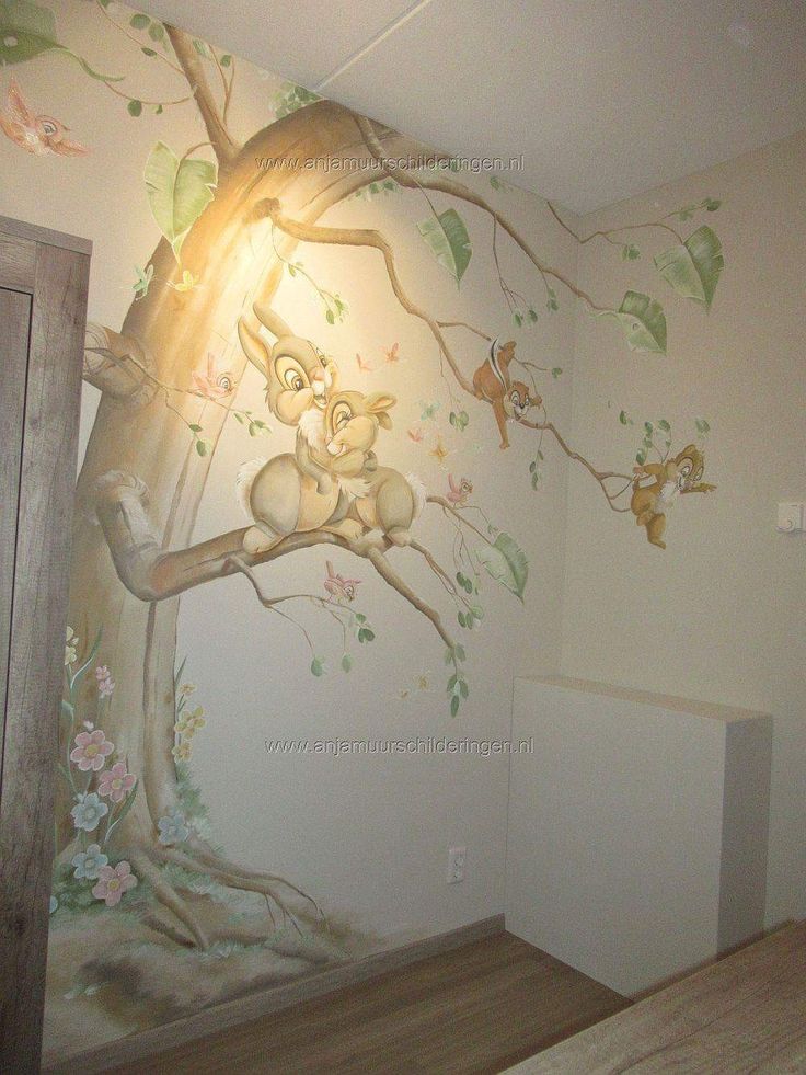 an empty room with a tree painted on the wall and stuffed animals hanging from it's branches