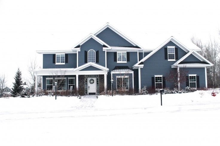 a large blue house with snow on the ground and trees in front of it,