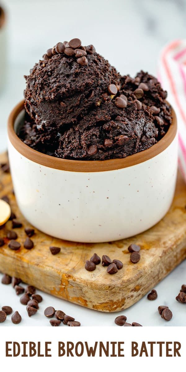 a bowl filled with chocolate brownie batter on top of a cutting board next to cookies