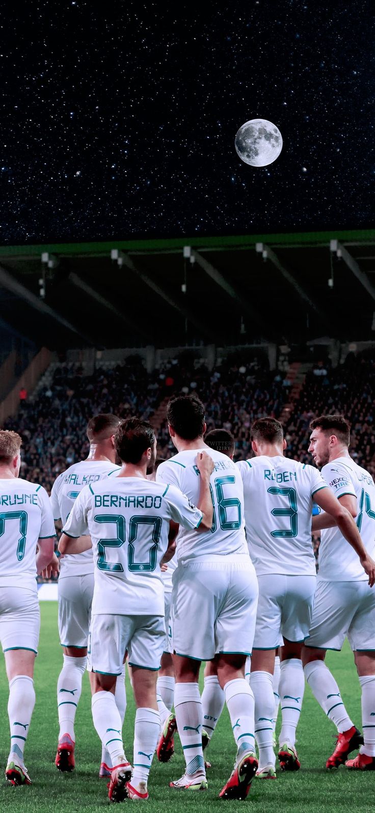 a group of soccer players huddle together on the field in front of an audience