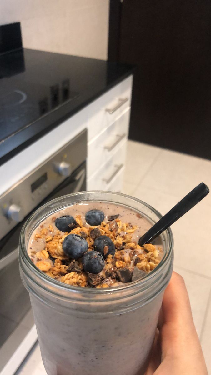 a person holding up a glass with some food in it on top of a counter