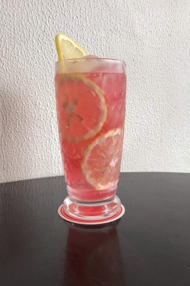 a glass filled with liquid sitting on top of a table next to a slice of lemon