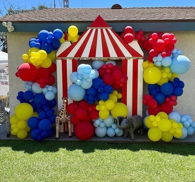 a circus tent is decorated with balloons and giraffes for an outdoor birthday party