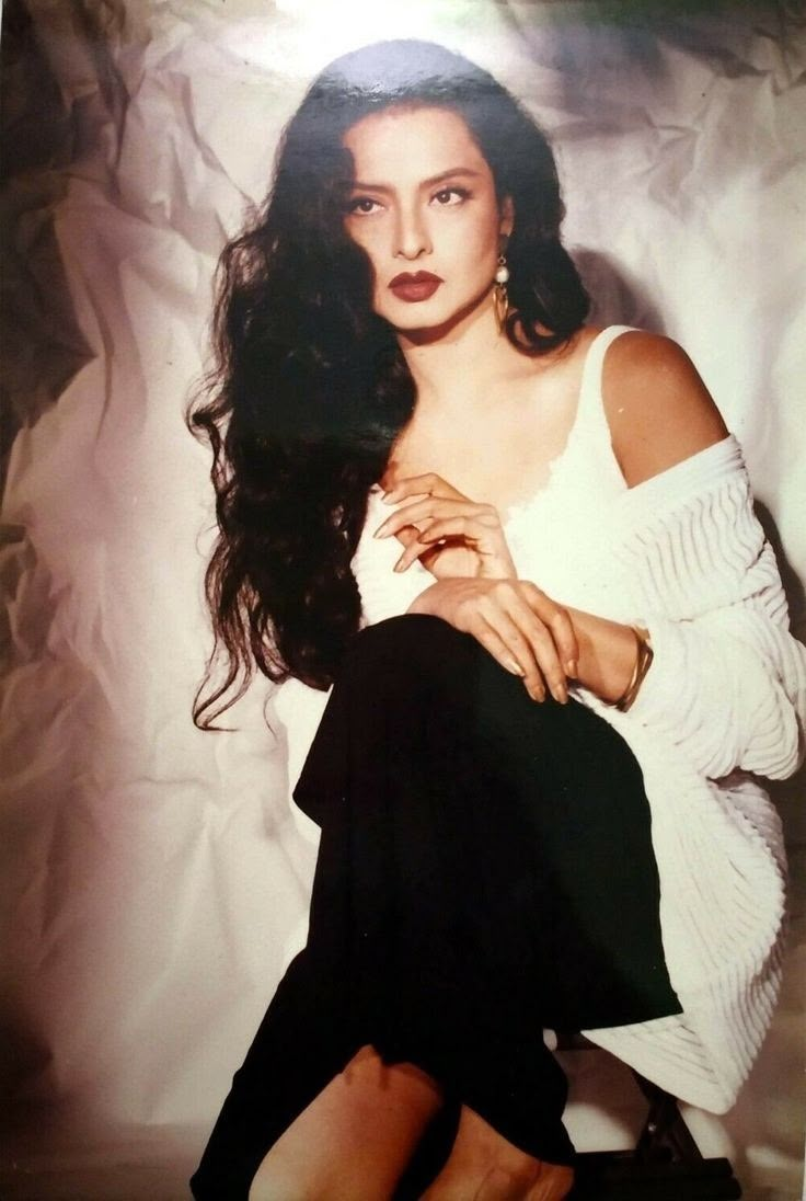 an old photo of a woman in white shirt and black skirt sitting on the floor