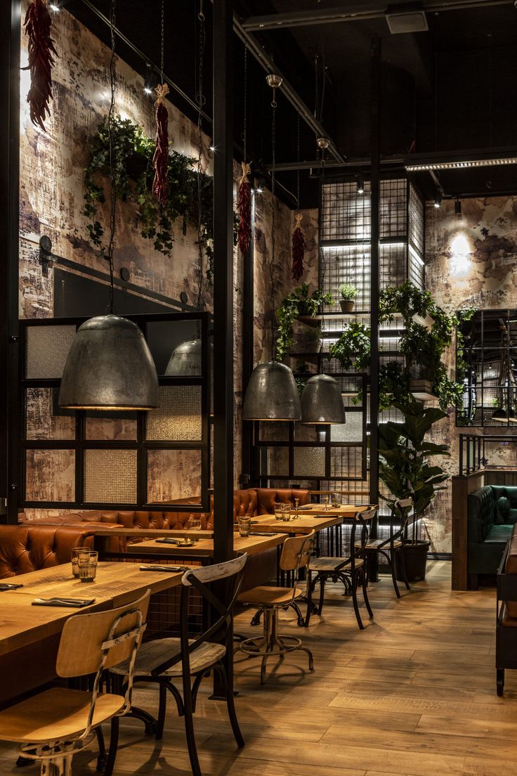 an empty restaurant with wooden tables and green couches, hanging plants and potted plants