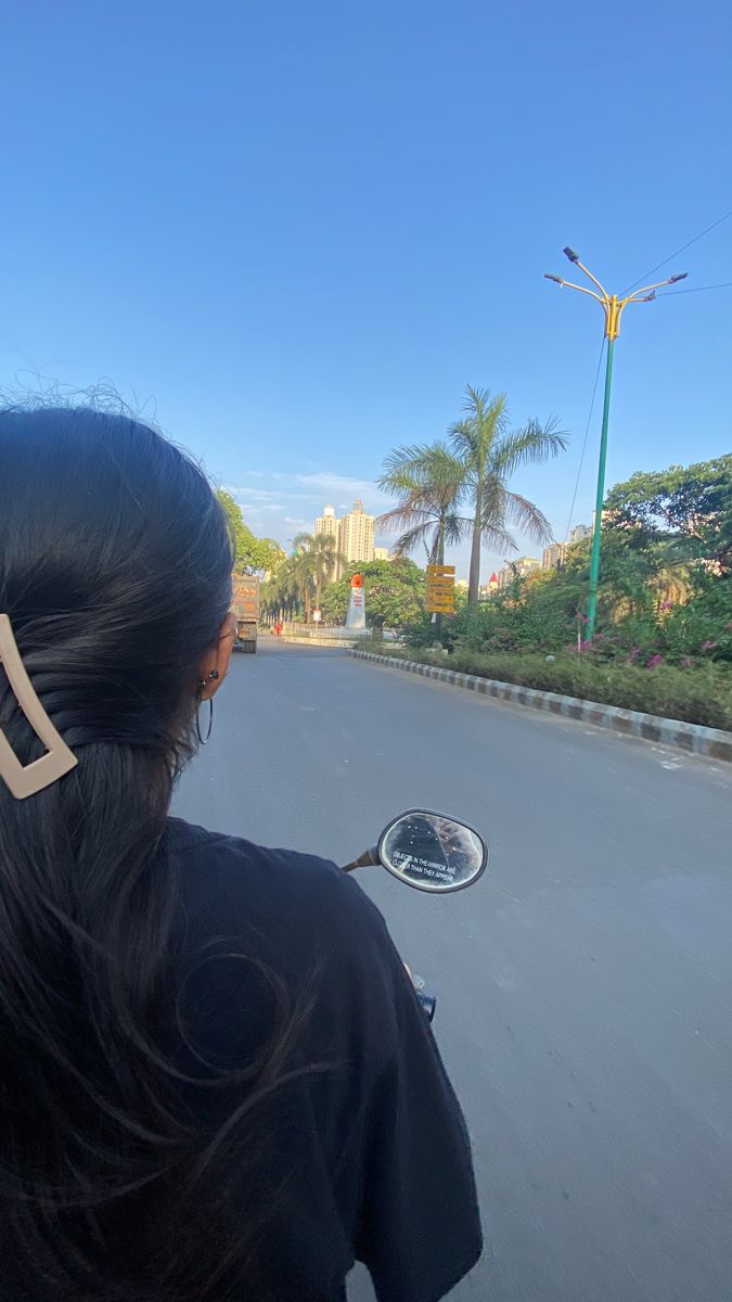 a woman riding on the back of a motorcycle down a street