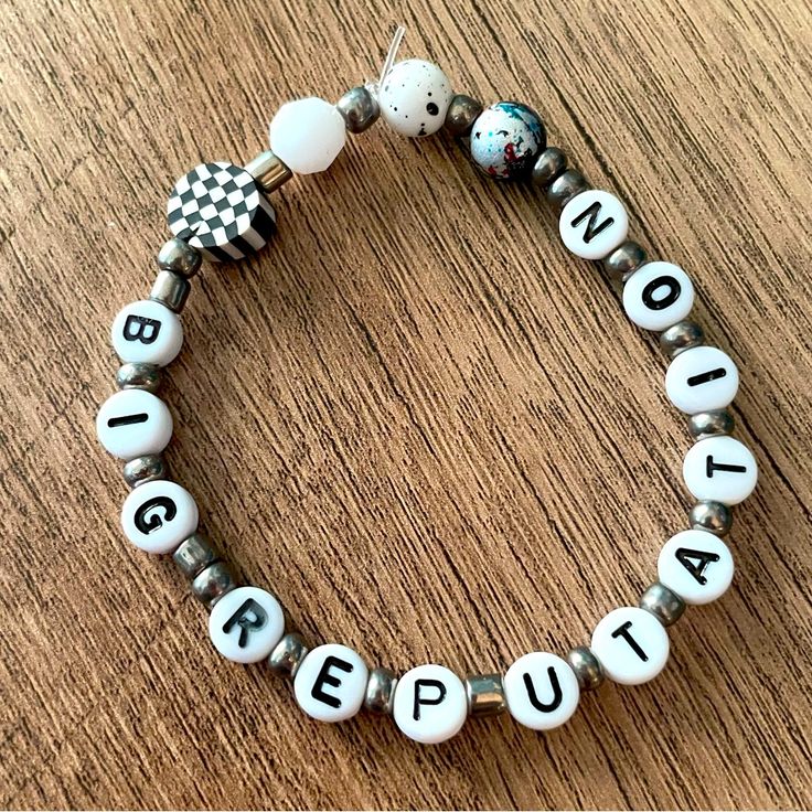 a close up of a bracelet on a table with words written in small letters and beads