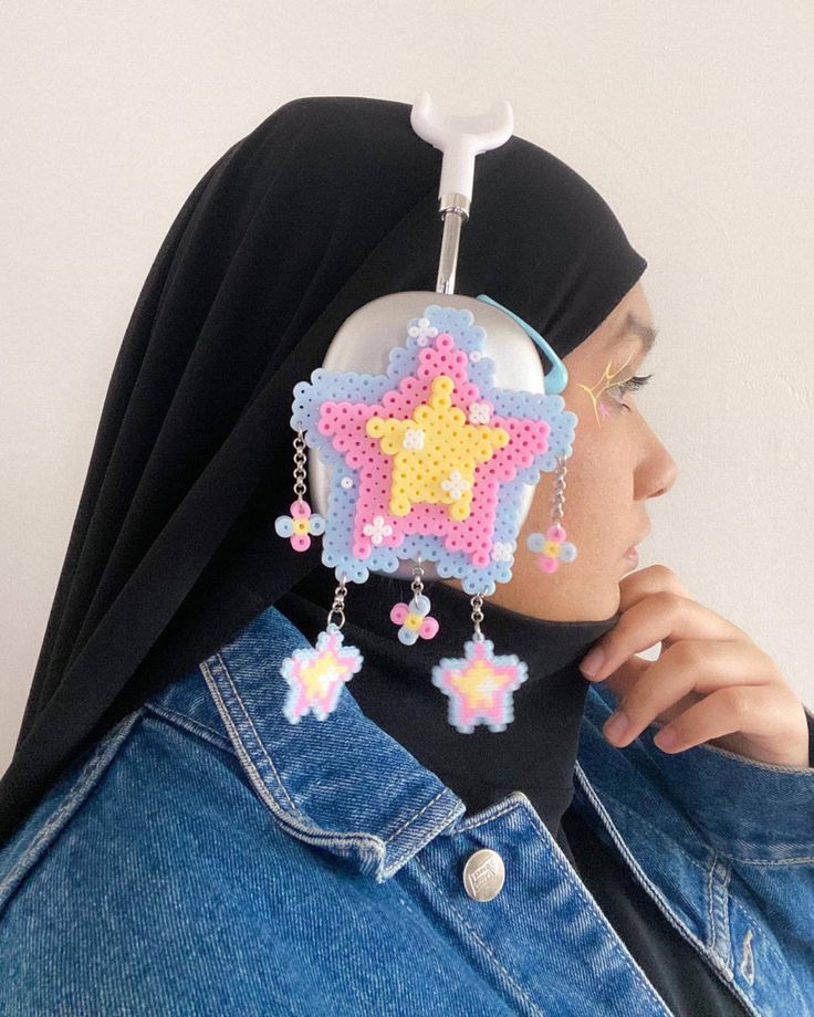 a woman wearing a hijab with a cross on it's head and some beads hanging from her ear