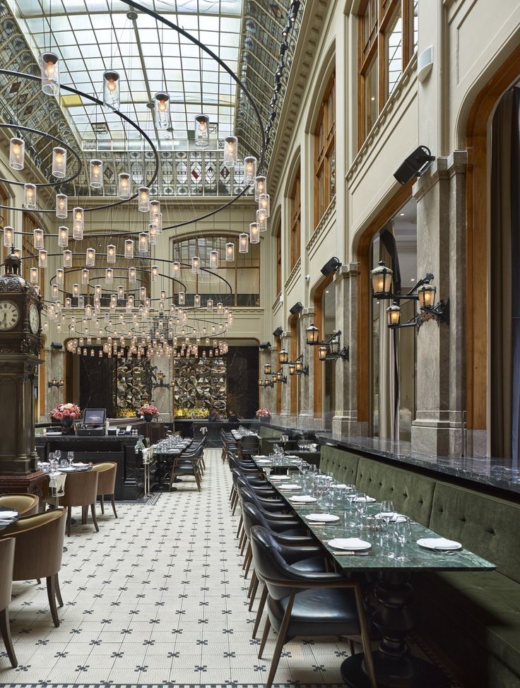 a restaurant with tables, chairs and chandeliers hanging from the ceiling