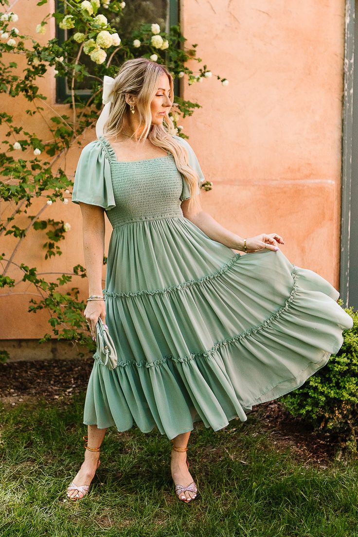 a woman in a green dress posing for the camera with her hand on her hip