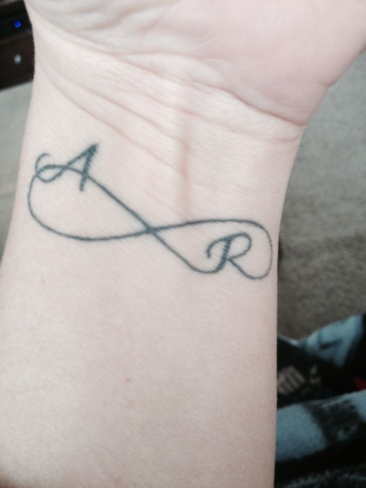 a person's wrist with a tattoo on it that has the letter a and an arrow