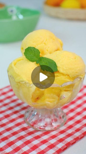 two scoops of ice cream sit in a glass dish on a red and white checkered tablecloth