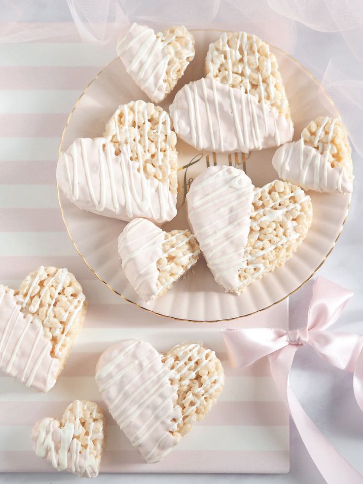 some heart shaped cookies on a plate next to a pink and white striped tablecloth