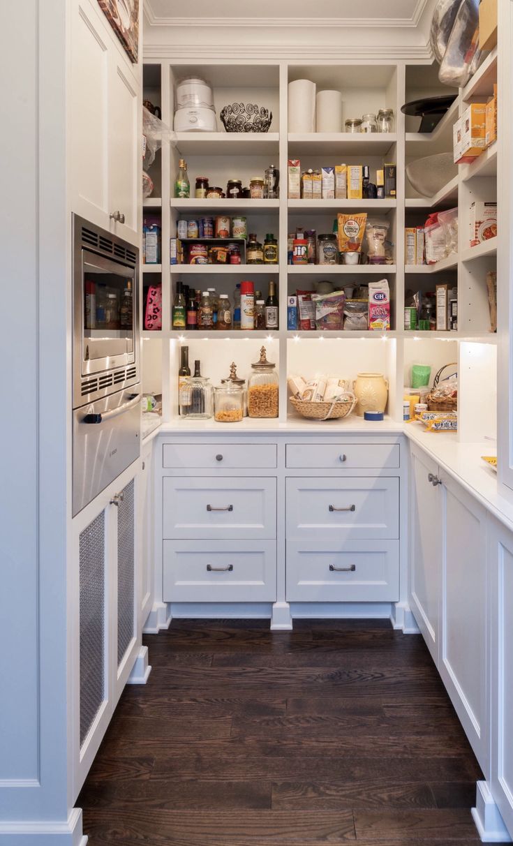 a kitchen with lots of white cabinets and drawers