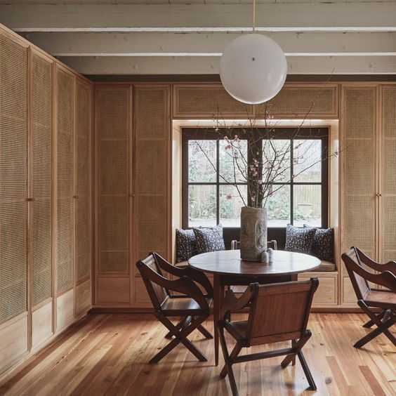 a table and chairs in a room with wood paneling on the walls, along with a window