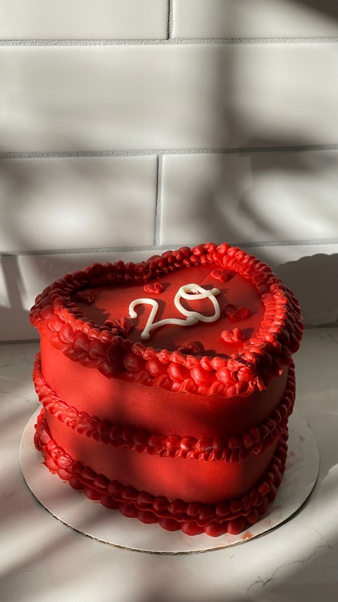 a red heart shaped cake with the number twenty on it