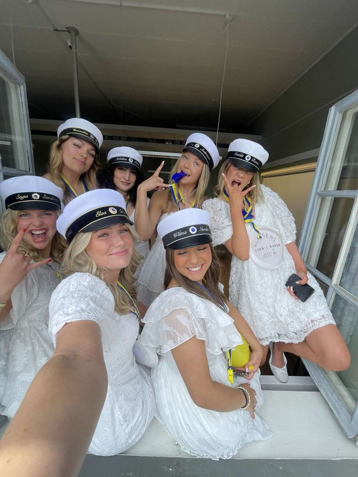 a group of women dressed in sailor hats posing for a photo with their hands up