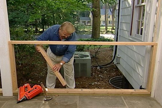 a man holding a bat in front of a window with tools on the ground next to it