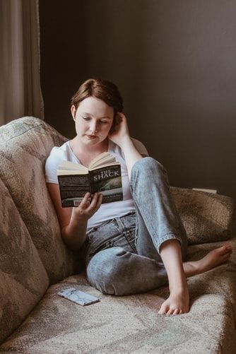 a woman sitting on a couch reading a book