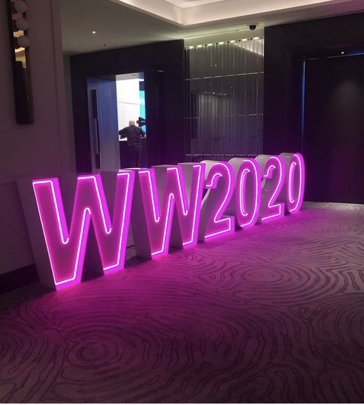 the word w is lit up with purple lighting in front of a black and white wall