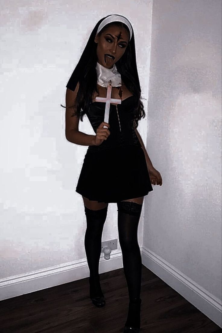 a woman dressed up as a nun holding a cross in her hand and wearing black stockings