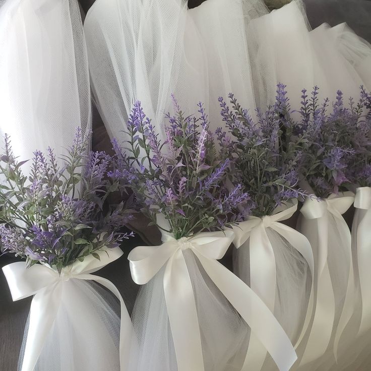 lavender flowers are tied to organ bags with white ribbons