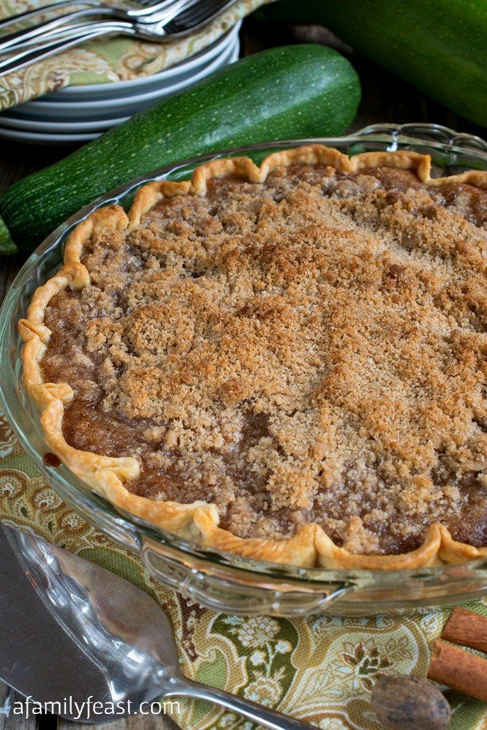 a pie sitting on top of a glass plate next to cucumbers and other food