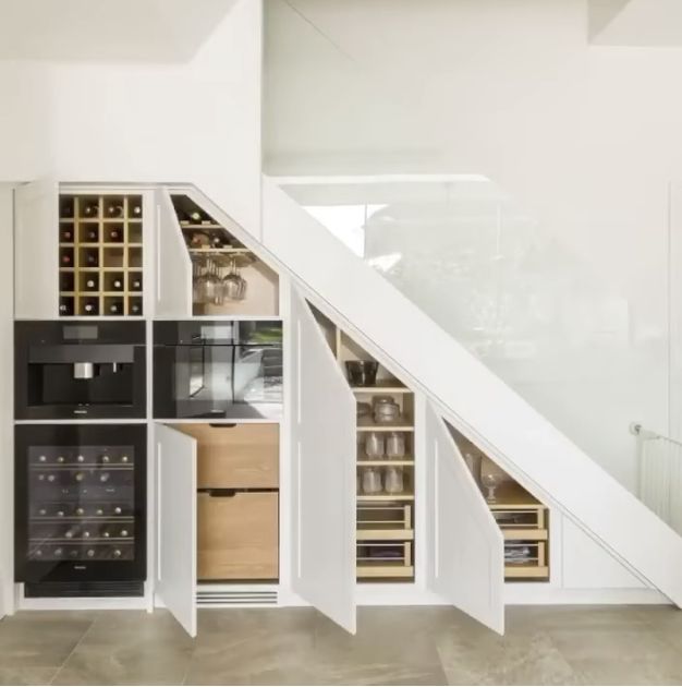 an open kitchen under a stair case in a room with white walls and flooring