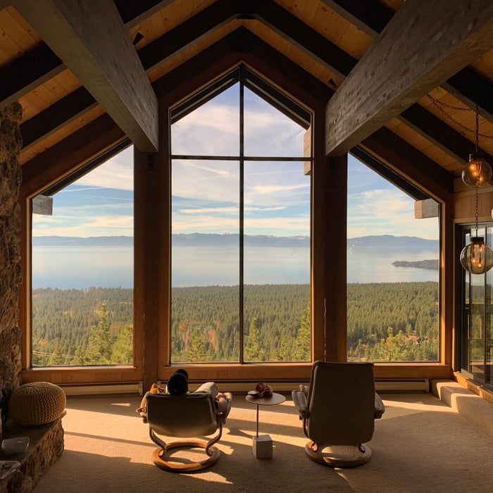 a living room filled with furniture and large windows overlooking the forest outside it's window panes