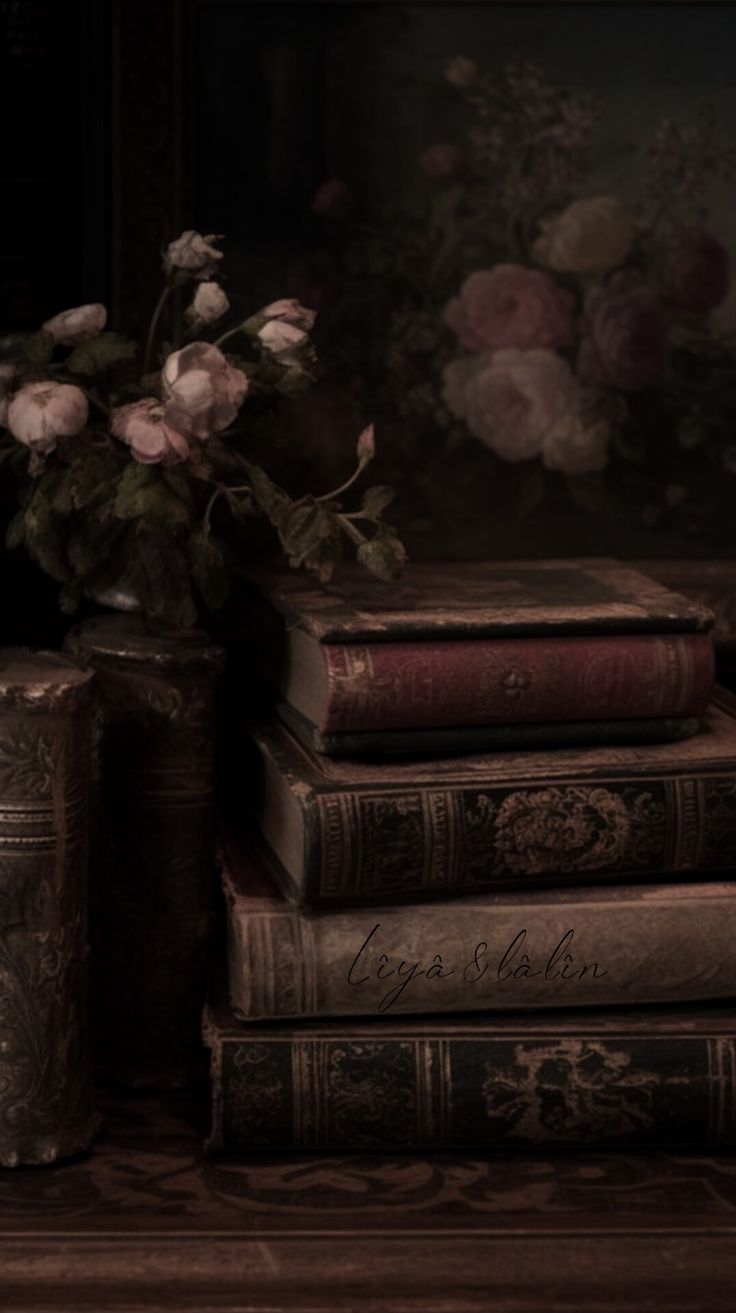 three books are stacked on top of each other in front of a vase with flowers