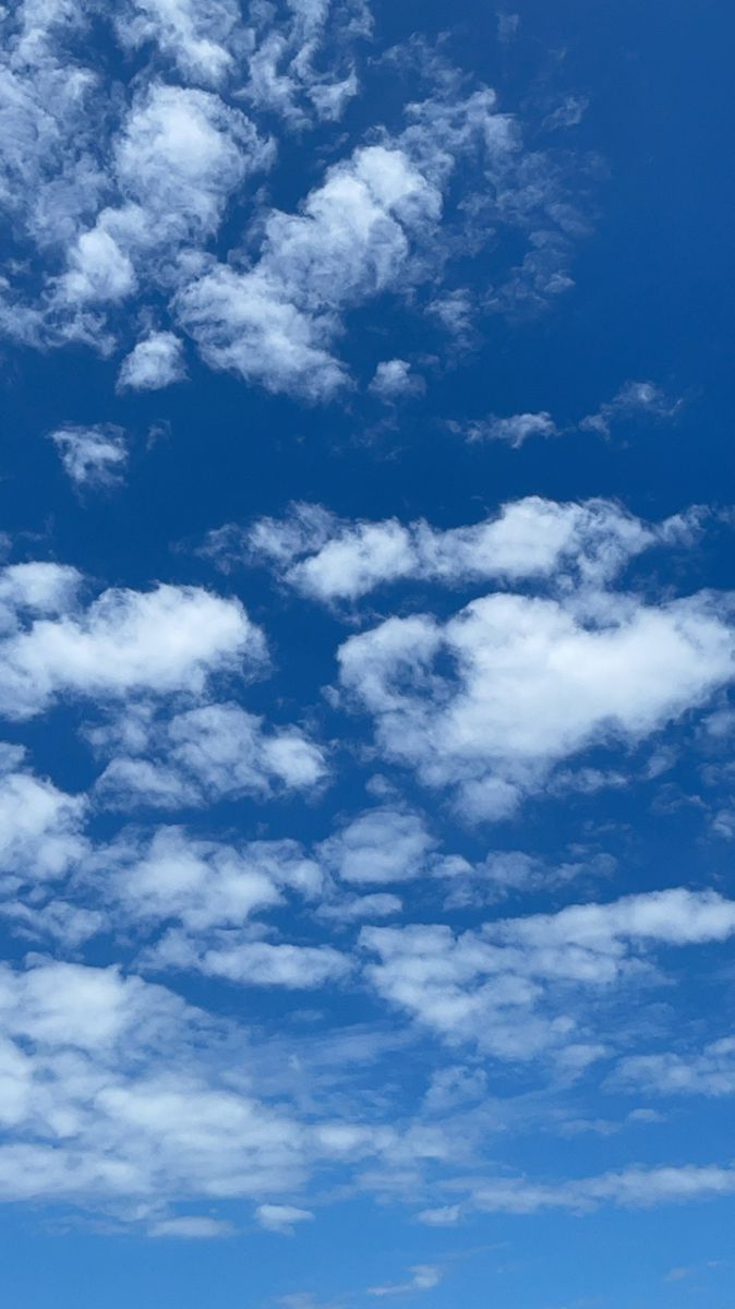 the airplane is flying high in the blue sky with fluffy white clouds above it,