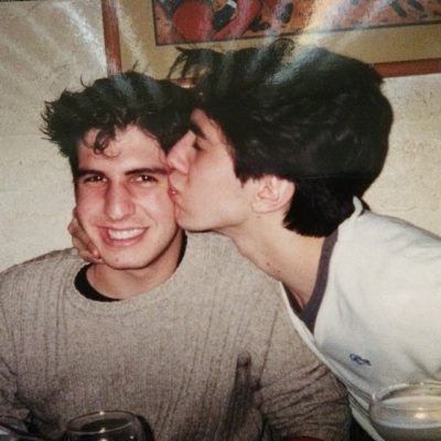 two young men kissing each other while sitting at a table