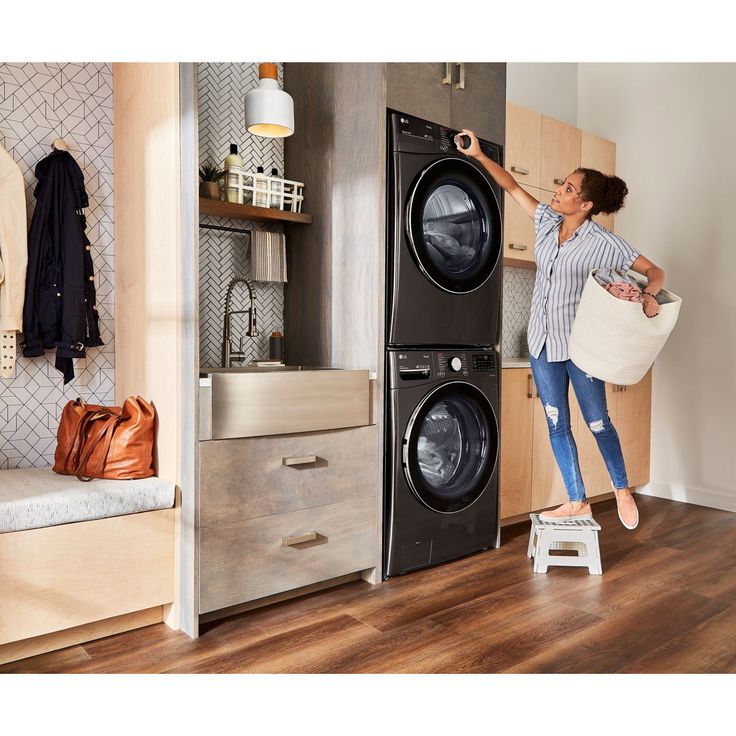 a woman holding a laundry bag in front of a washer and dryer