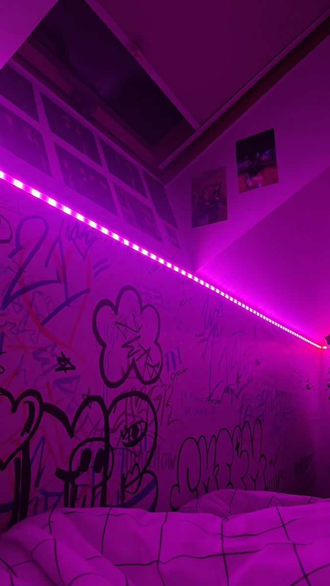 a bedroom with purple lights and graffiti on the walls, along with a white bed