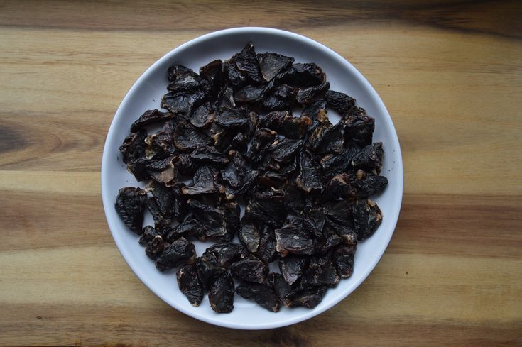 a white bowl filled with raisins on top of a wooden table