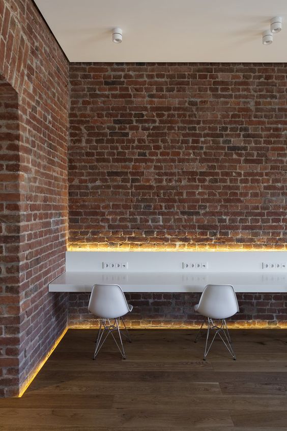 three white chairs sitting next to each other in front of a brick wall with lights on it