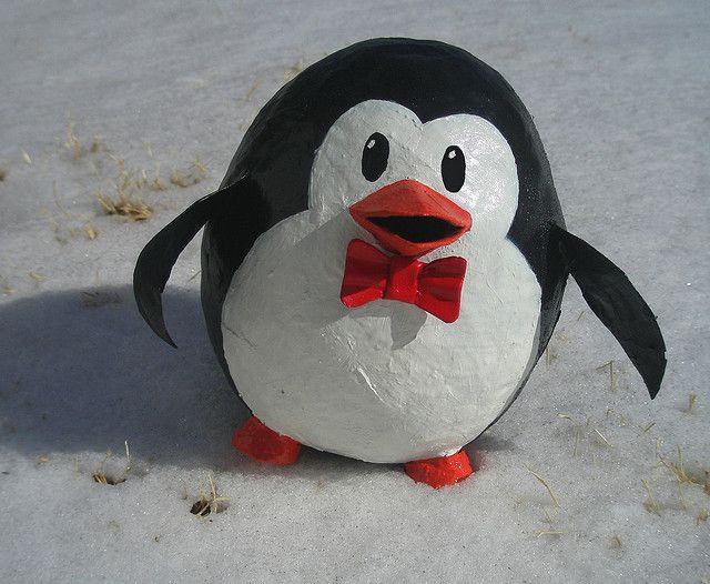 a penguin with a red bow tie standing in the snow