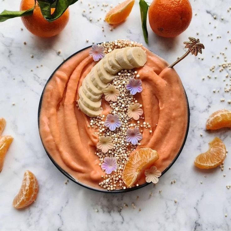 a bowl filled with oranges and bananas on top of a marble table next to sliced oranges