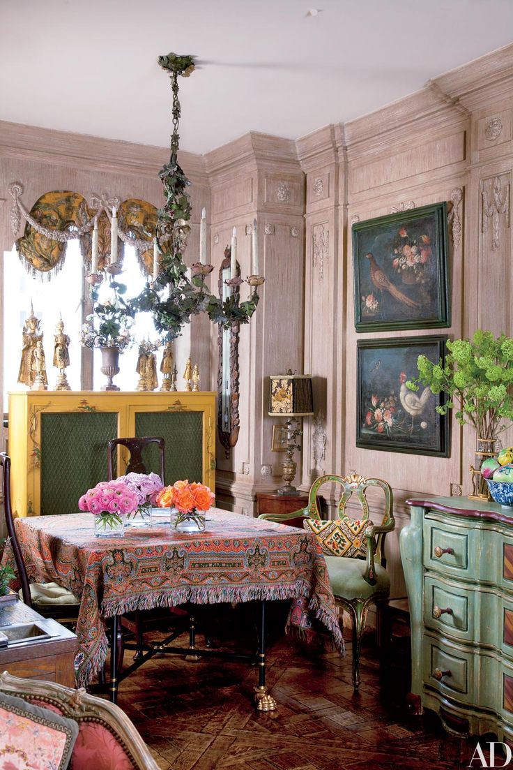 an ornate dining room with antique furniture and flowers on the table in front of a fireplace