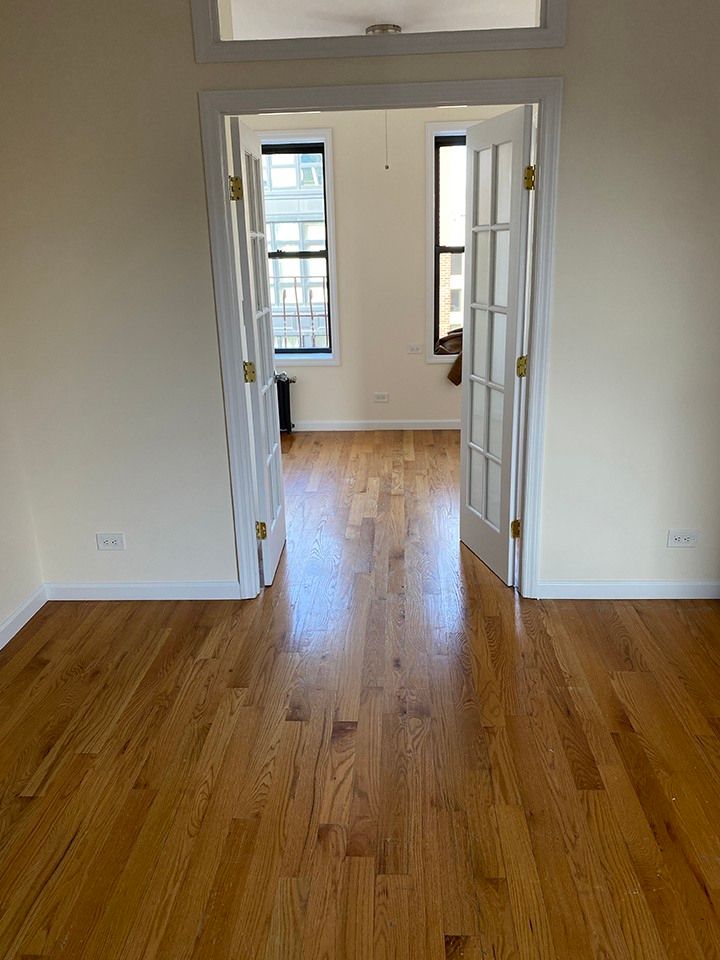 an empty room with hard wood floors and white trim on the doors, windows, and ceiling fan