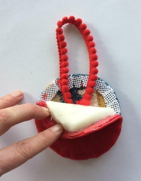 a hand is holding a red and white purse with beads on it's handle